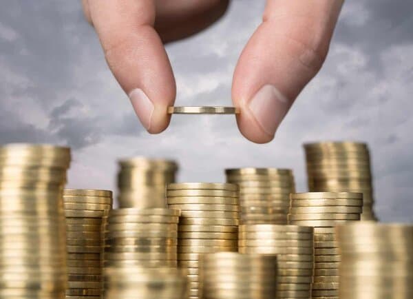 pile of coins with a hand adding another coin coppering up for Slimming World meals on a budget