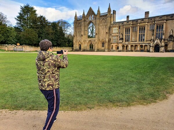 A boy in a camo jacket taking a photo of Newstead Abbey