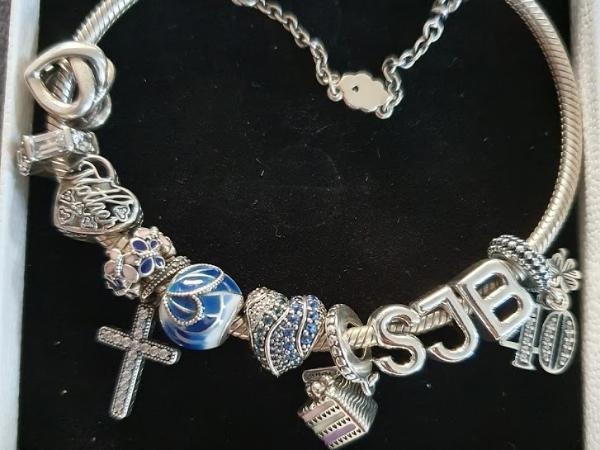 Silver Pandora charm bracelet with various charms on black surface