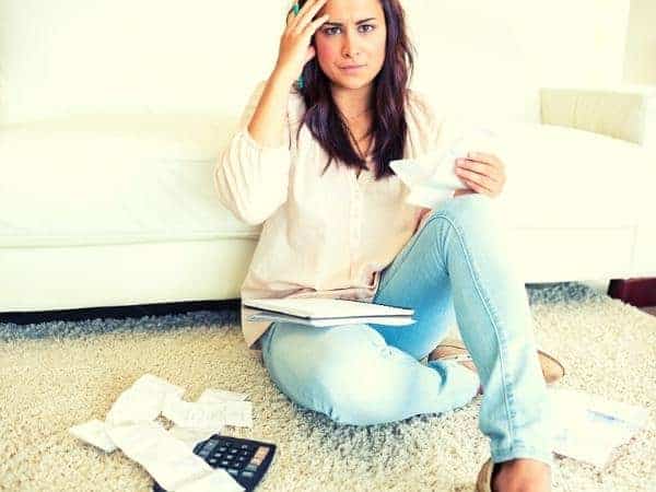 woman sitting on floor worrying about bills