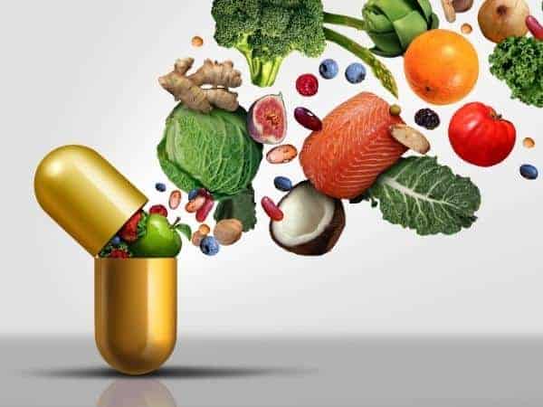 A vitamin capsule with various healthy foods bursting out into the air