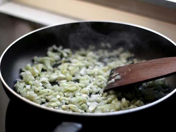 onions being fried in a black frying pan close up