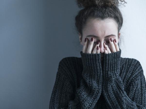 Lady covering her face looking fed up and depressed.