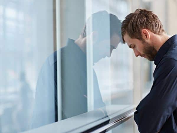 man with head against a window struggling with his mental health