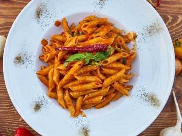 bowl of pasta in a tomato sauce topped with a chilli and basil leaves