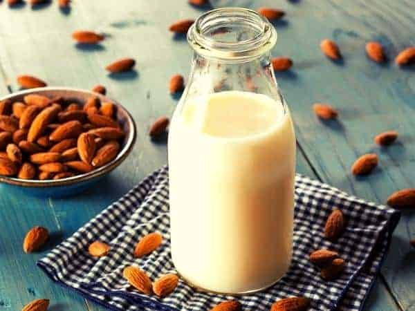 small glass bottle of milk with almonds, almond milk for a healthy extra a choice