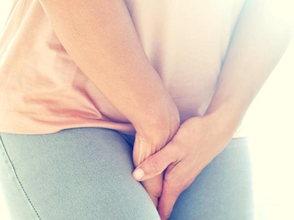 Lady holding hands between her legs as she has bladder weakness with pelvic floor difficulties