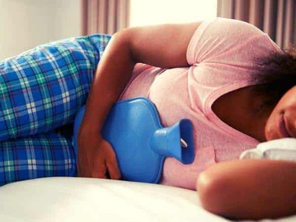 Lady in pyjamas with a hot water bottle for period pains