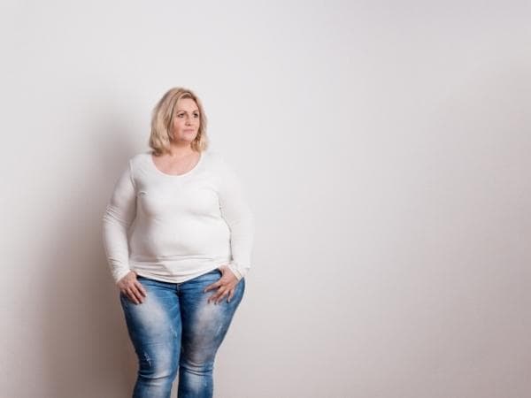overweight lady standing in front of white wall
