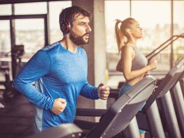 Two fit adults running on treadmills