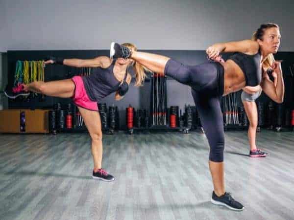 Two women kickboxing on a grey floor
