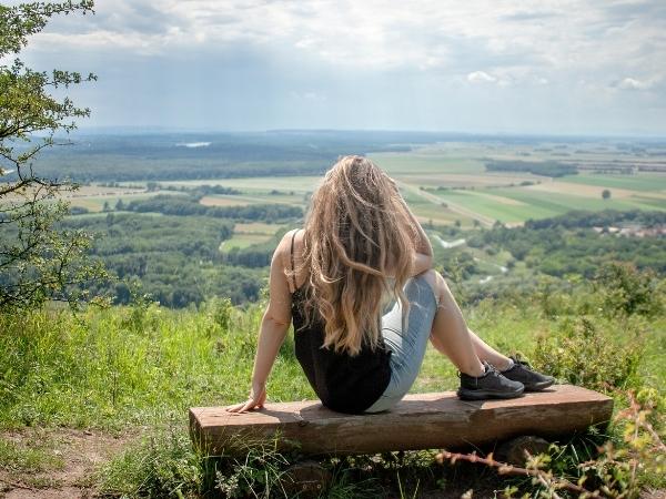 A woman sitting on a bench in front of a mountain