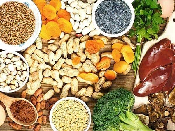 iron rich food spread on a table including liver, broccoli, nuts and dried apricots
