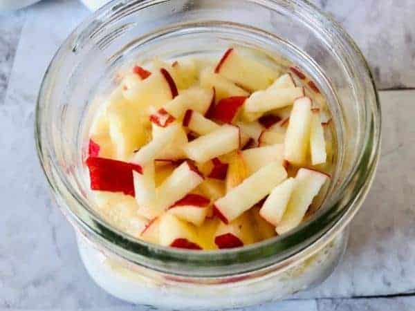 glass jar with yoghurt and oats topped with diced apple.