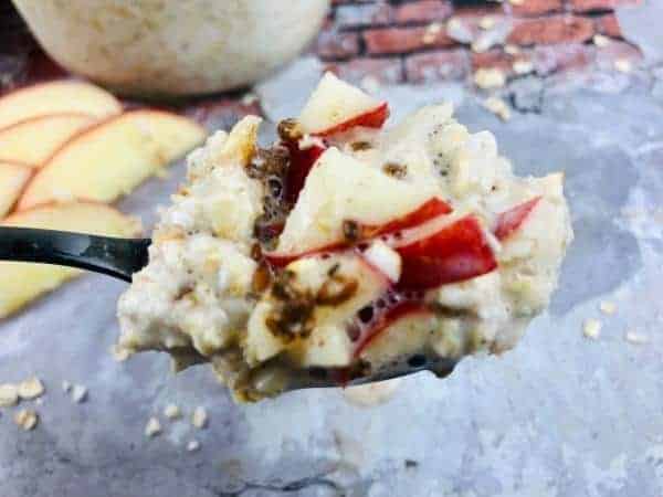 overnight oats with apple and cinnamon on a spoon.