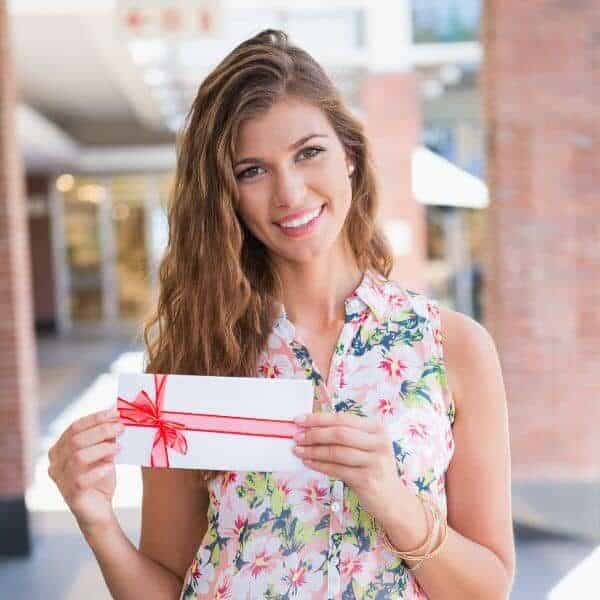A woman holding a gift card for home cleaning services from Abby's Cleaning Service