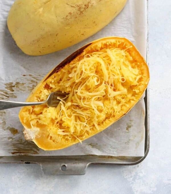 Heritage squash ‘Spaghetti’ with pale yellow skin and cooked flesh separating into spaghetti-like strands after baking.
