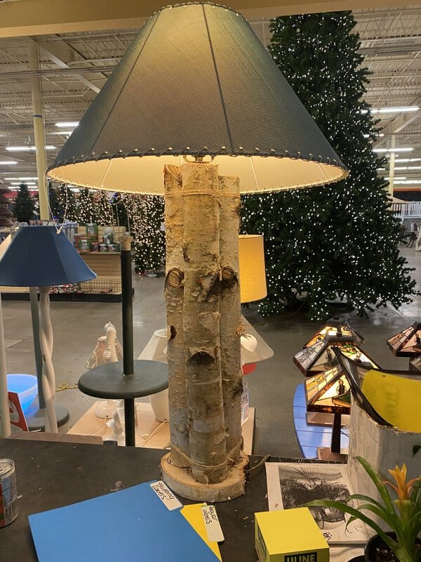 A rustic wooden log lamp with a beige shade in a store.