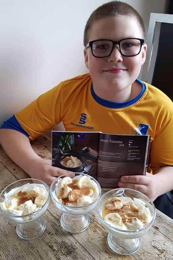 Ben holding sweet banana pot recipe with three of the desserts in front of him