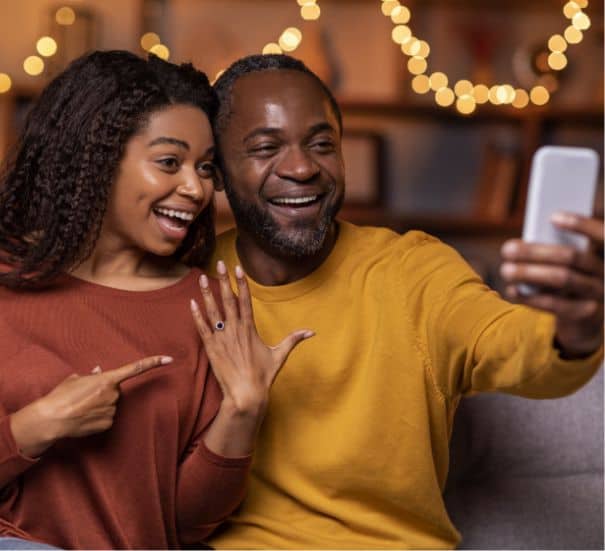 Happy Black couple taking an engagement selfie to show off the ring