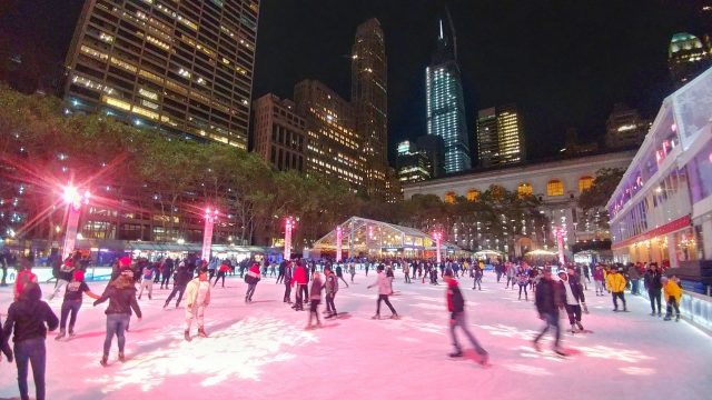 ice skaters on the ice at the rink at Bryant Park at night