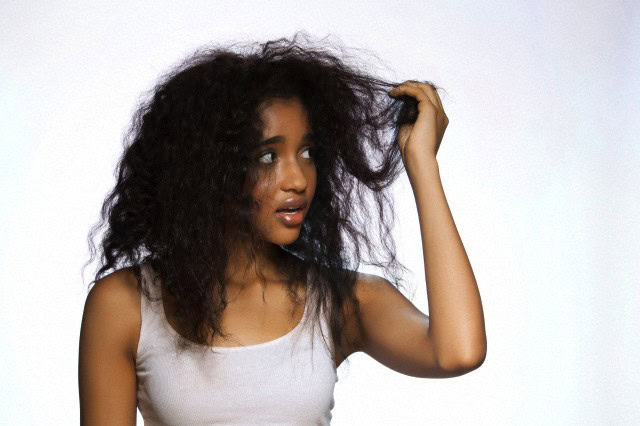 Young woman holding hair against white background