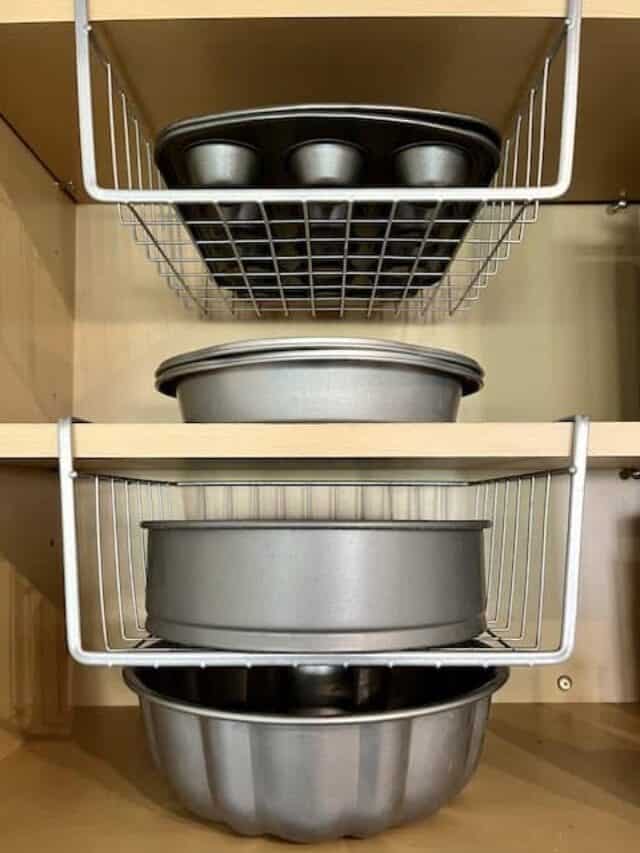 A kitchen cupboard with baking pans on shelves