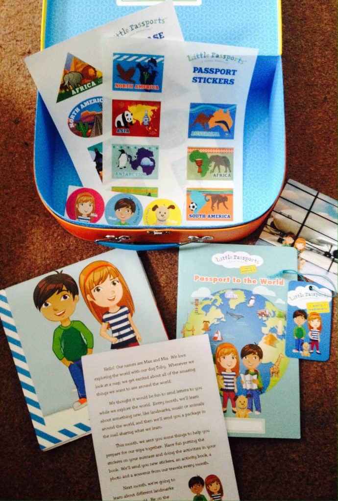 Contents of Little Passports suitcase. Stickers, passport, postcard, suitcase tag, intro