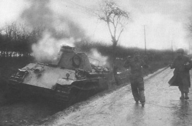 Amerikaanse soldaat begeleidt een Duitse bemanningslid van een uitgeschakelde Panther-tank tijdens de Slag bij Elsenborn Ridge.