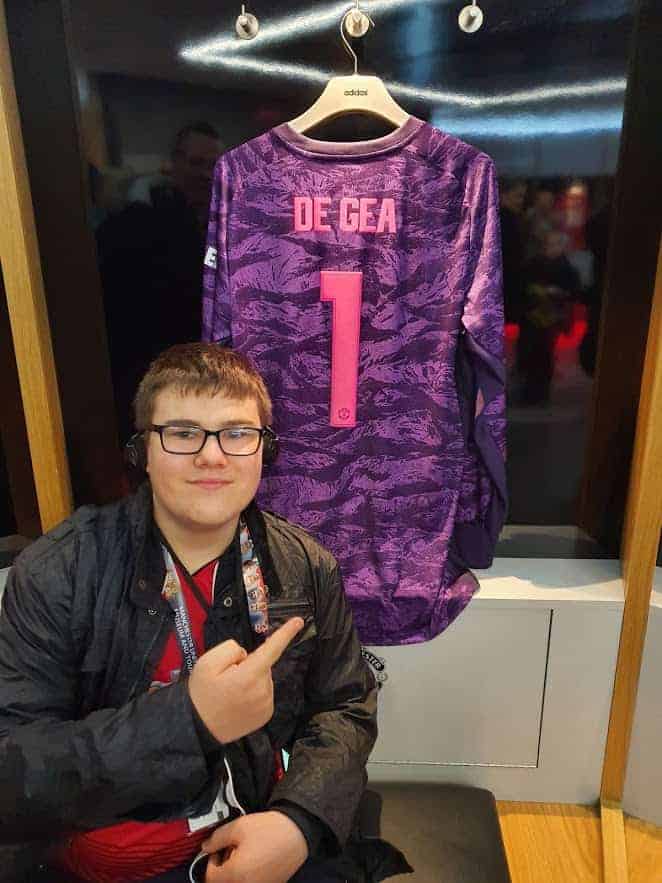 Young boy standing in front of a purple Degea shirt