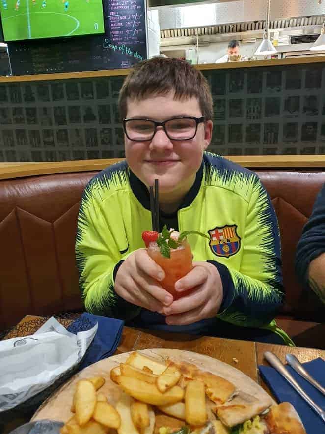 Young boy holding a mocktail with a smile on his face