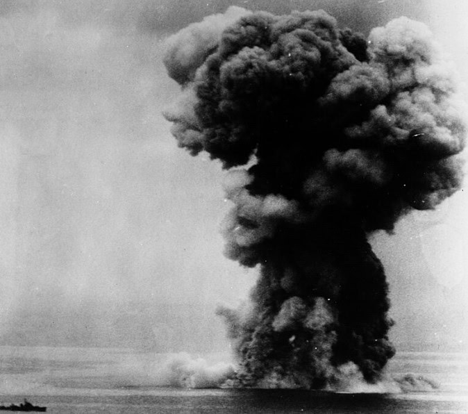 Afbeelding toont de explosie en ondergang van het Japanse slagschip Yamato in 1945, getroffen door torpedo's en bommen.