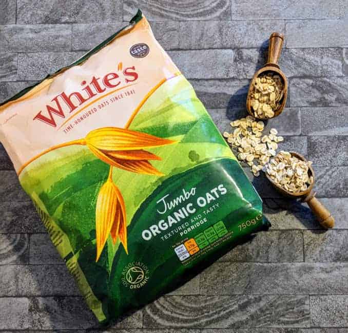 bag of whites oats with some spilled next to it with two wooden small scoops