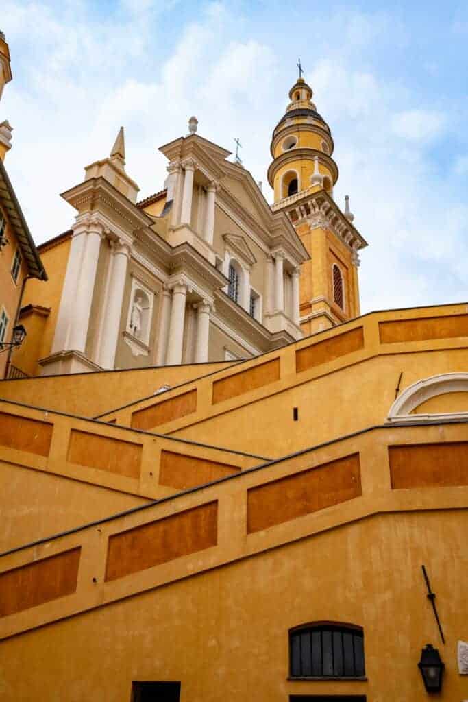 Baroque church and bell tower above ochre walls in Menton, a must-see during any weekend trip.