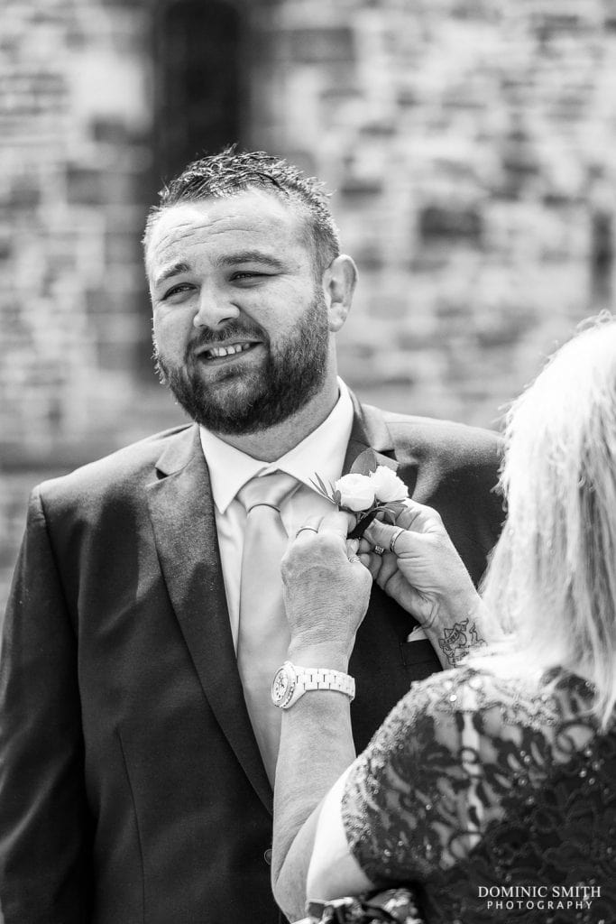 Groom having his buttonhole done