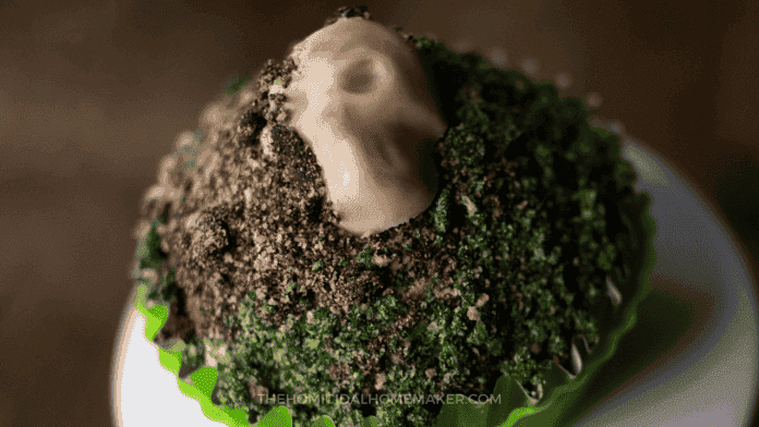 Close-up of a Demon Wind butternut squash cupcake with crushed cookie dirt and a skull candy decoration.