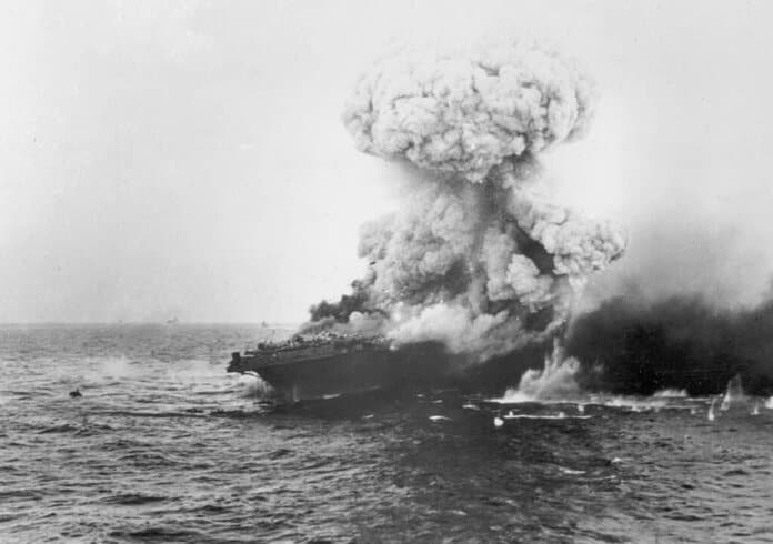 Explosie op USS Lexington tijdens de Slag in de Koraalzee, 8 mei 1942; rookpluim stijgt op, Yorktown zichtbaar aan horizon.