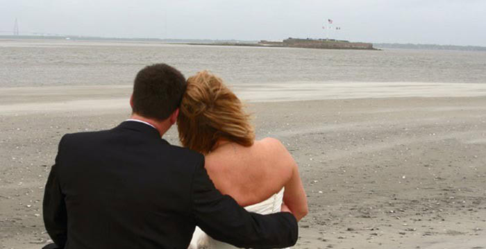 Bride and Groom sitting on the beach looking out on the water. Wedding dinner cruise Charleston SC