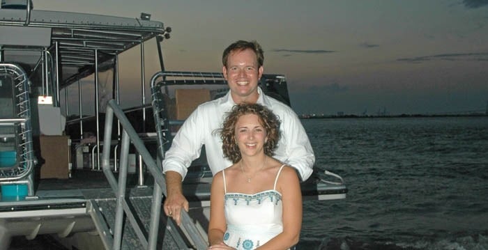 Bride and groom taking a picture on the Sandlapper Tours boat with the sunset in the background. Wedding dinner cruise Charleston SC