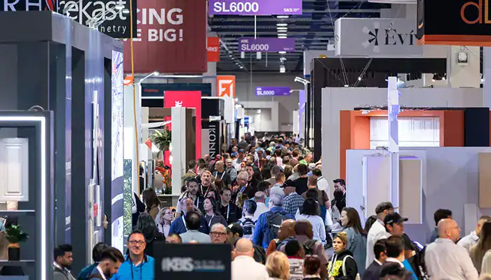Attendees moving between open exhibition booths during a busy trade show