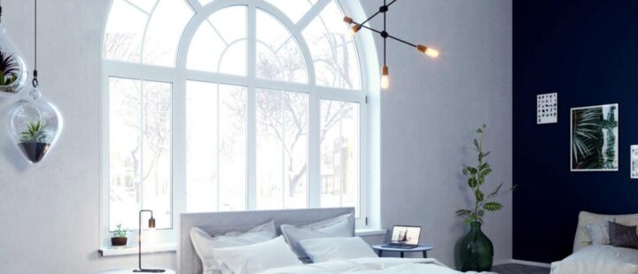 Schlafzimmer mit Bett vor großem Rundbogenfenster