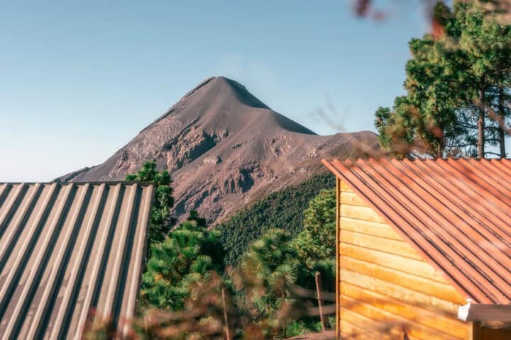 Exterior of a cabin at OX Expeditions campsite with view of Fuego volcano in the distance