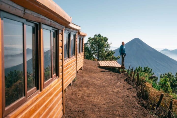 Hiker standing at edge of Acatenango campsite deck with Agua volcano in the background
