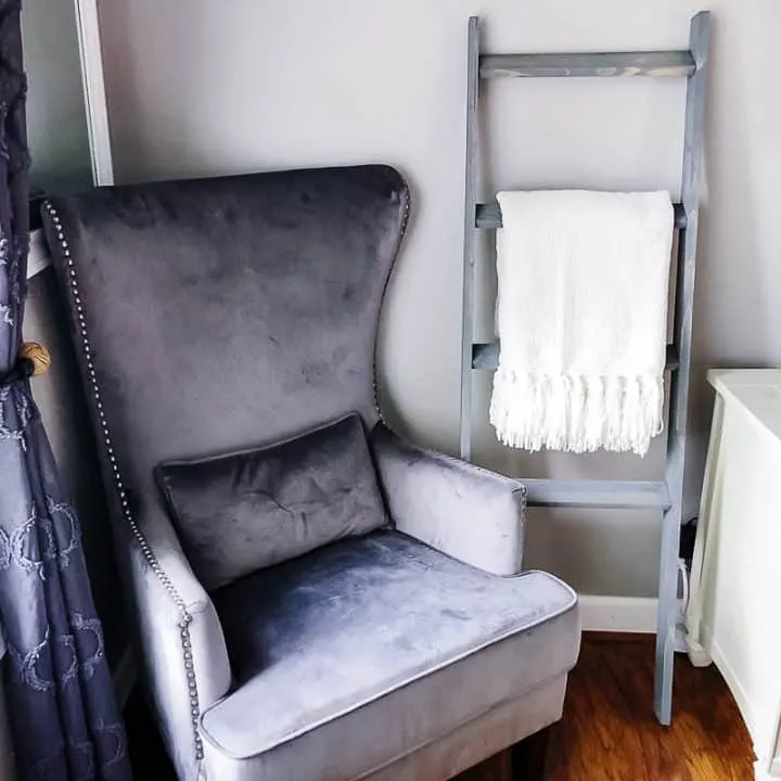 Living room with large gray chair and a blanket ladder against the wall