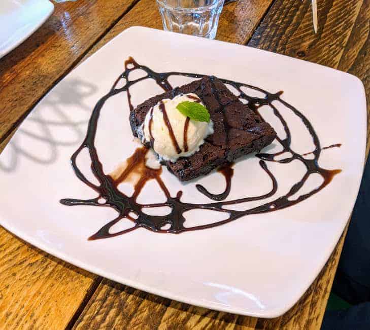 Chocolate fudge brownie on white plate on wooden table