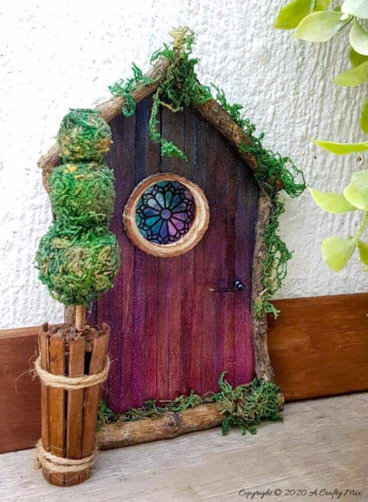 Welcome the fae folk into your home with this gorgeous stained glass fairy door. Made with things you probably already have in your craft cupboard the door doubles up as a night light. #FairydoorDIY #FairyDoorIdeas #ACraftyMix #MakeAFairyDoor #MiniatureStainedGlass #AlcoholInk
