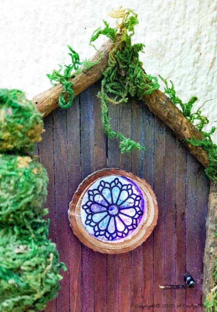 Welcome the fae folk into your home with this gorgeous stained glass fairy door. Made with things you probably already have in your craft cupboard the door doubles up as a night light. #FairydoorDIY #FairyDoorIdeas #ACraftyMix #MakeAFairyDoor #MiniatureStainedGlass #AlcoholInk