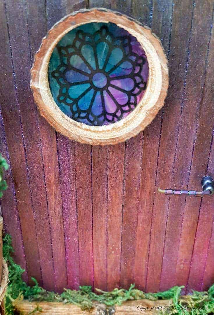 Welcome the fae folk into your home with this gorgeous stained glass fairy door. Made with things you probably already have in your craft cupboard the door doubles up as a night light. #FairydoorDIY #FairyDoorIdeas #ACraftyMix #MakeAFairyDoor #MiniatureStainedGlass #AlcoholInk