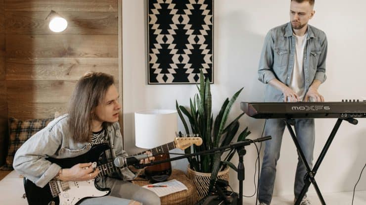 Teens practicing music at home, young musicians with electric guitar and keyboard, cozy indoor setting, creative music session, indoor rehearsal, musical instruments, home music studio, learning music, casual band practice, youthful musicians.