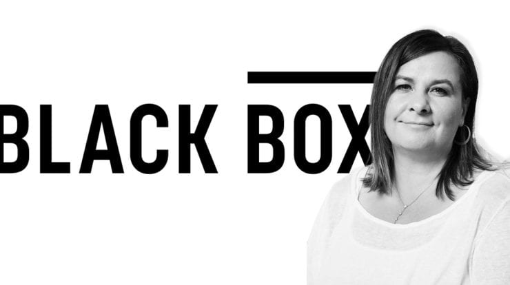 Empowered woman standing in front of Black Box music industry logo, symbolizing innovation and leadership in the music and entertainment technology sector.